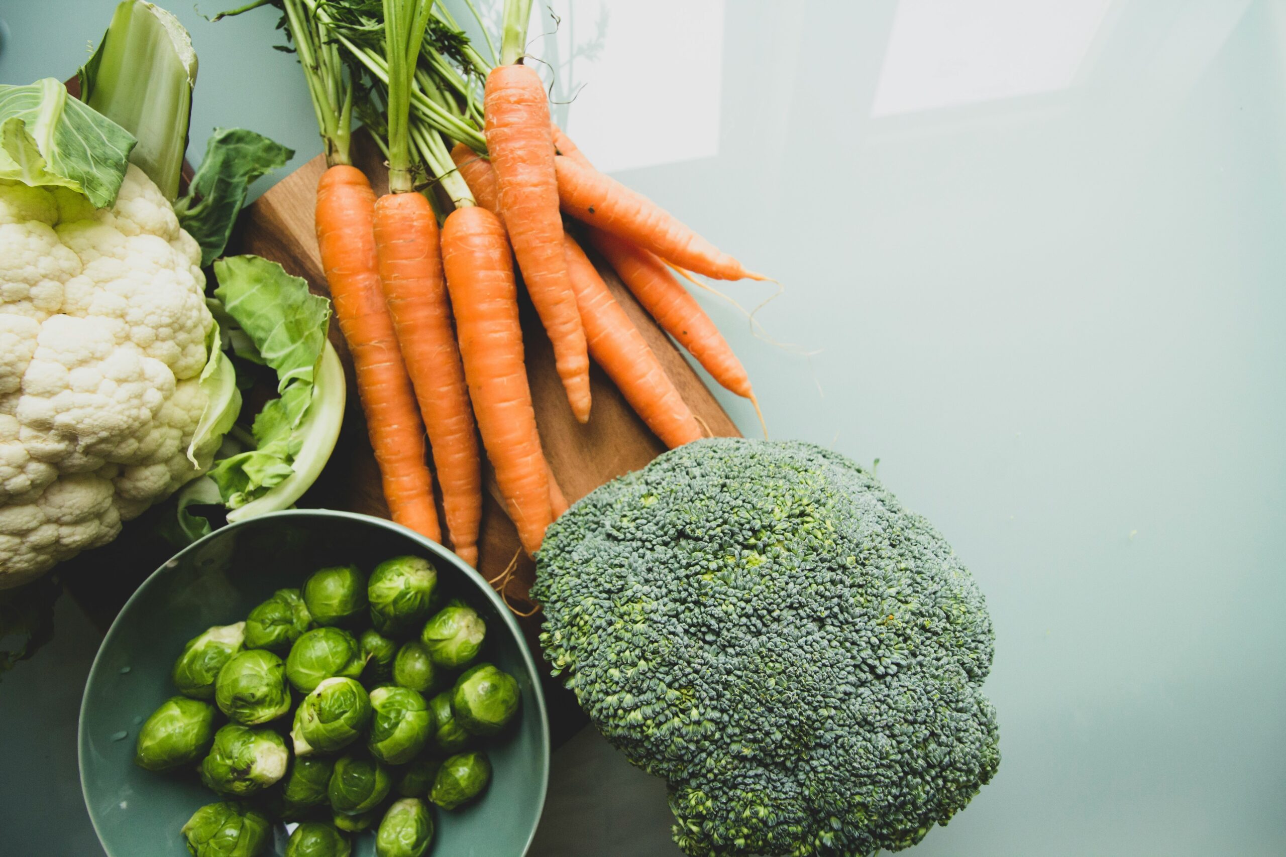A bowl filled with vibrant organic vegetables like carrots, cucumbers, and spinach