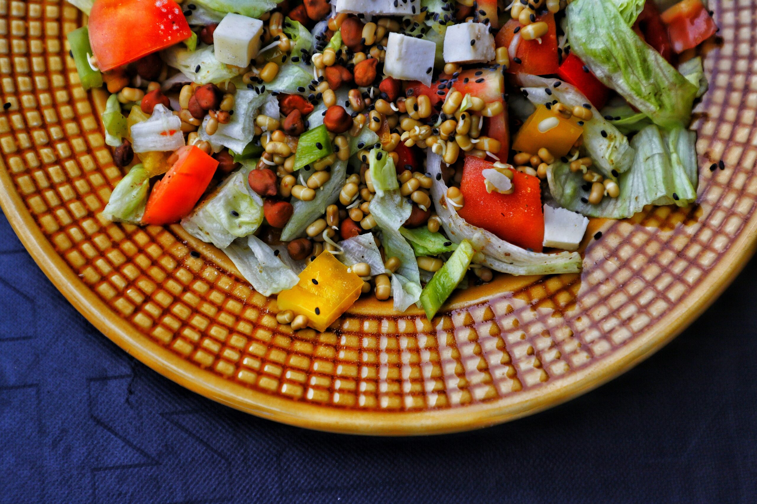 A bowl of colorful quinoa salad topped with fresh organic vegetables and avocado slices
