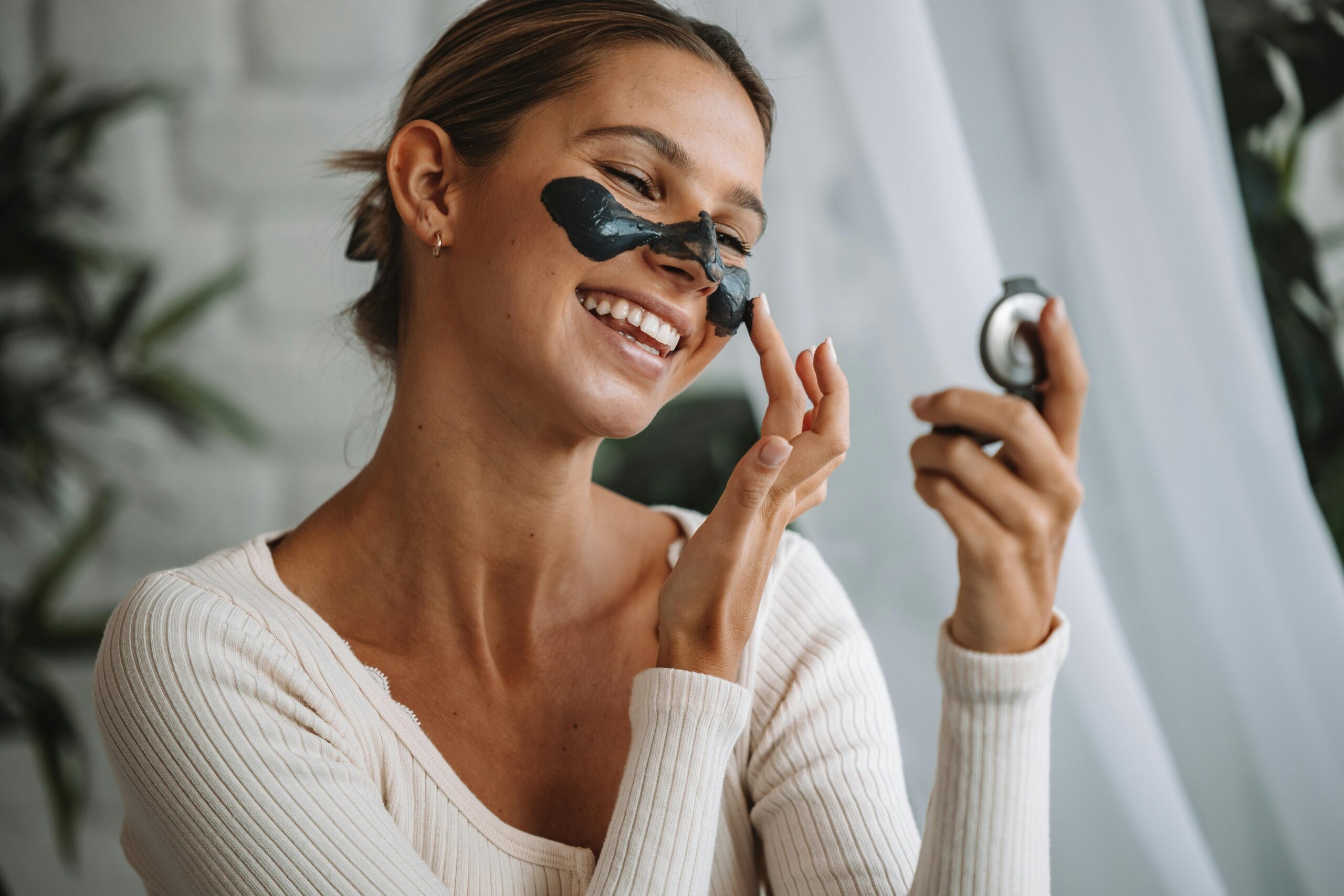 Woman applying avocado mask on her face with visible smile