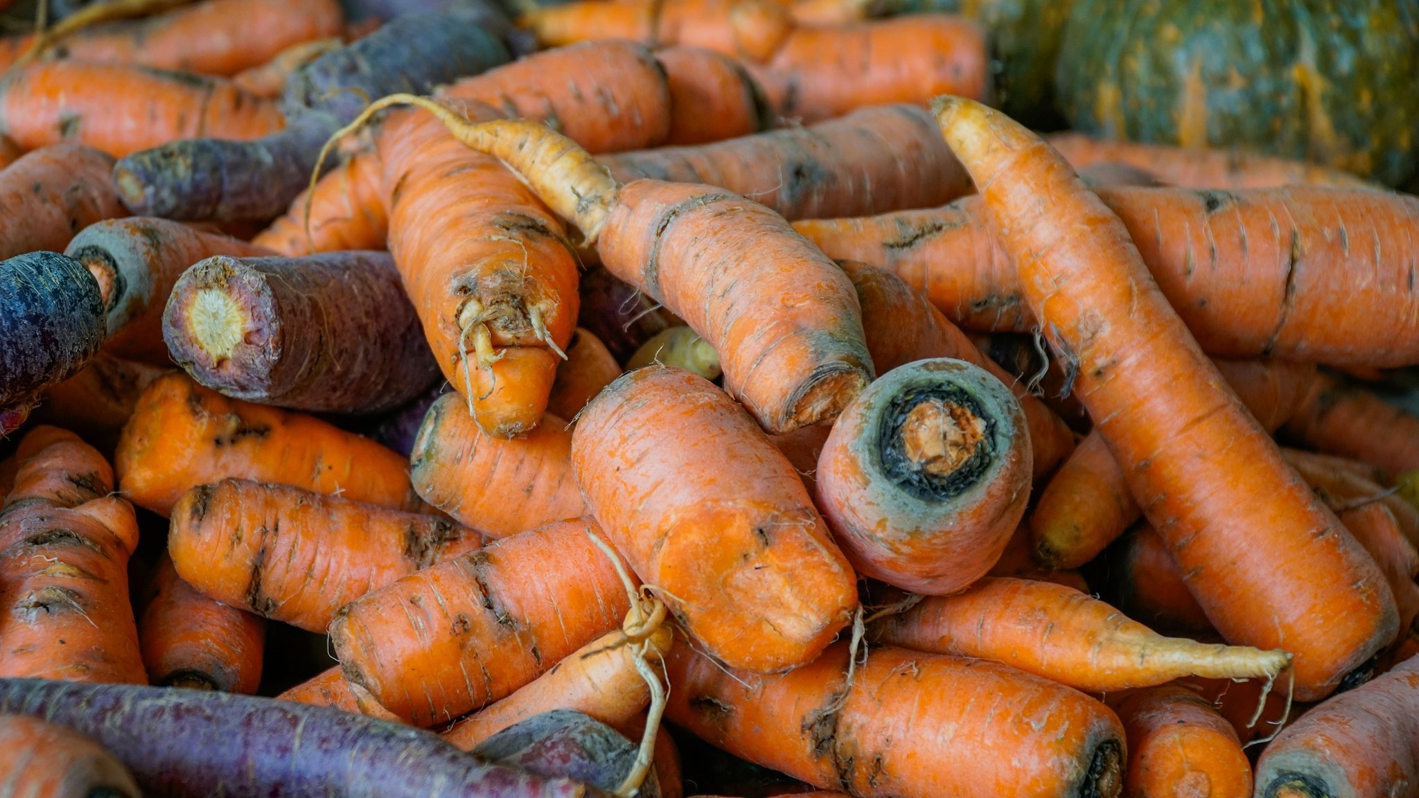 A bowl of fresh organic carrots next to skincare products
