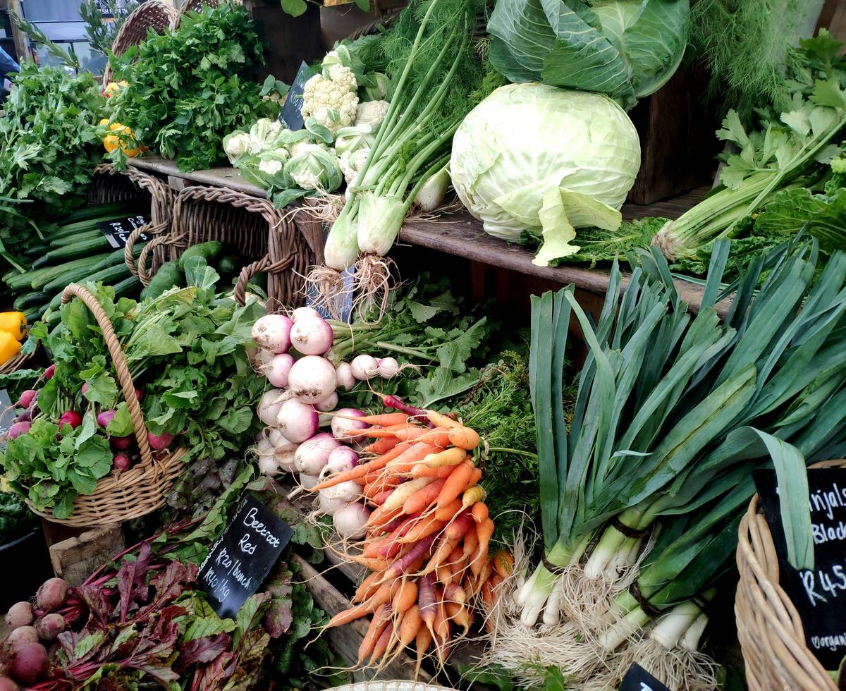 A basket filled with fresh organic vegetables including carrots, spinach, and bell peppers.