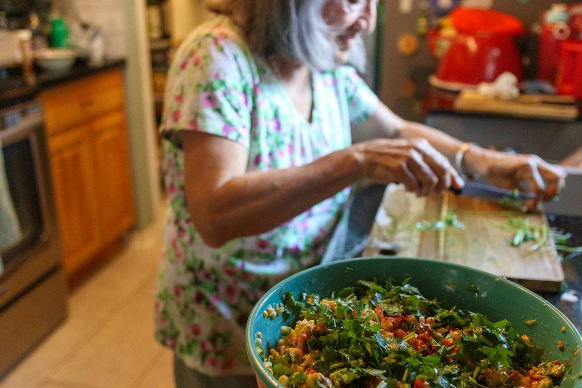 A vibrant basket filled with fresh organic carrots, kale, spinach, and tomatoes.
