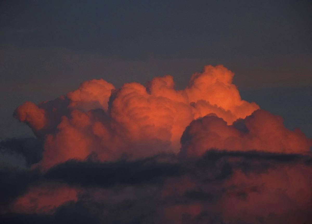 a large cloud is in the sky at sunset