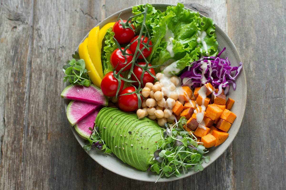 Infographic showing skin benefits of organic vegetables: carrots (vitamin A for cell turnover), spinach (iron + folate for circulation), bell peppers (vitamin C for collagen), beets (betaine for detox), broccoli (sulforaphane for UV protection)