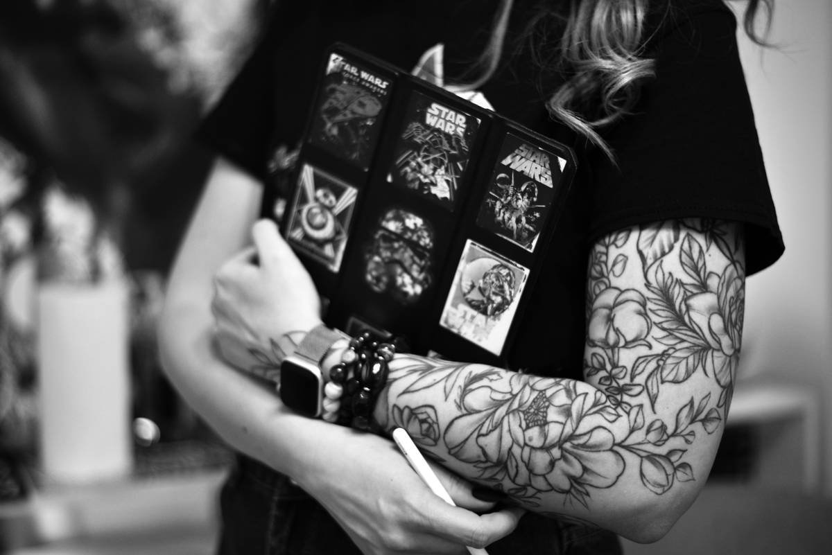 a woman with tattoos on her arm holding a cell phone