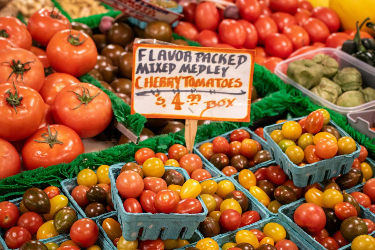 Small baskets are filled with red, yellow, orange, and even green cherry tomatoes, creating a visually appealing arrangement.